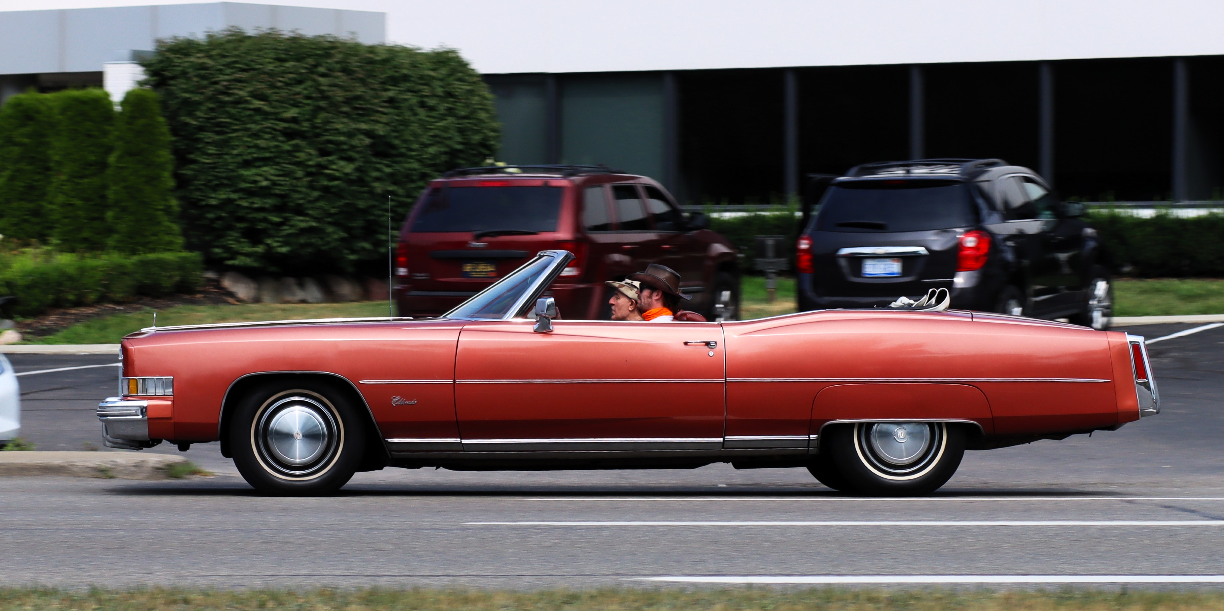Photograph of a reddish orange mid-70s Cadillac Eldorado convertible seen from the left side.